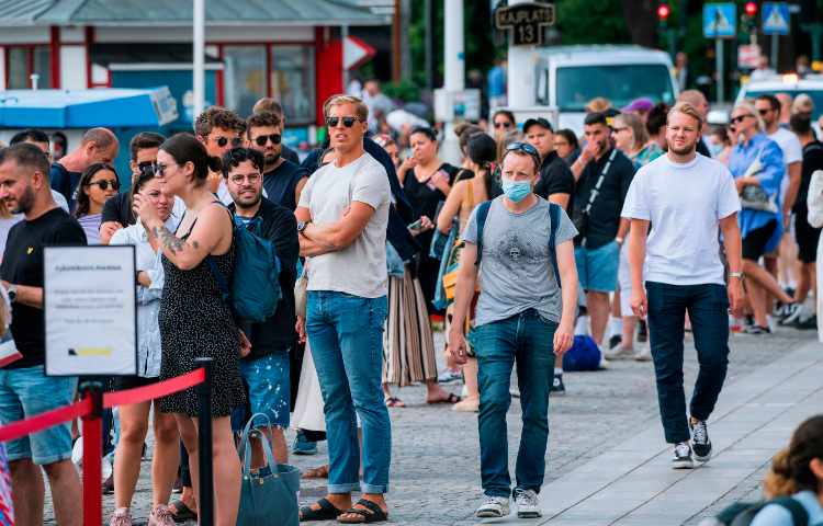 Persone in fila in mascherina a Stoccolma 