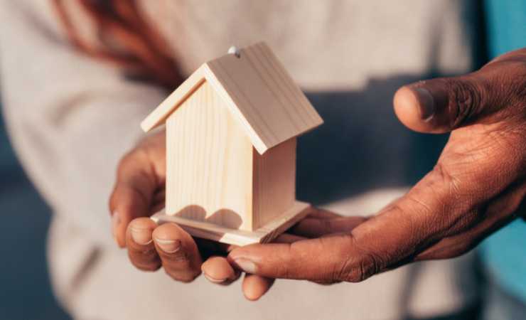 Persone tengono in mano una casa
